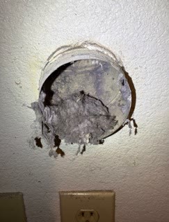 A wall dryer outlet nearly closed off by lint